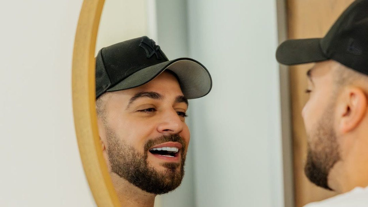 A client smiling at his new veneers in the mirror at Doctor Laleh Dental Aesthetics