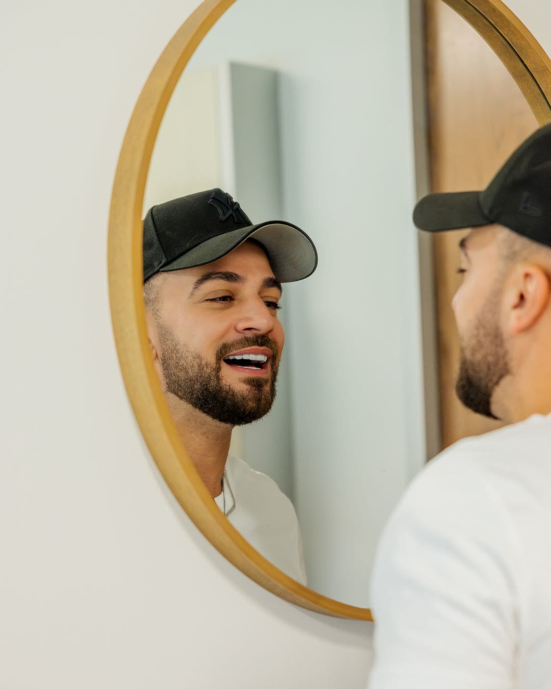 Patient smiling at the mirror during the reveal of his new no-prep veneers